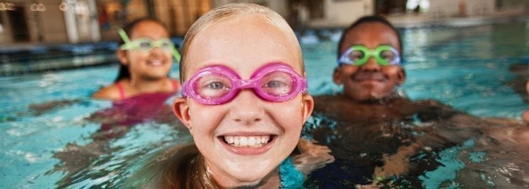3 kids in pool wearing goggles